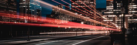 A city street at night with light trails from a passing vehicle