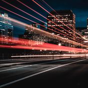 A city street at night with light trails from a passing vehicle