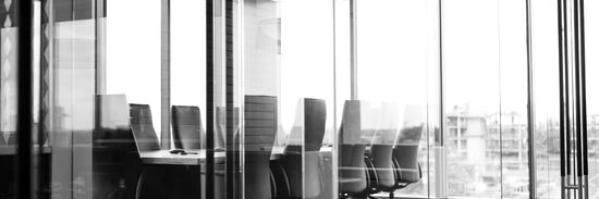 A boardroom of a modern office building with large floor-to-ceiling windows overlooking the city