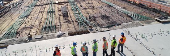 A row of people wearing hardhats overlooking a construction site