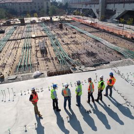 A row of people wearing hardhats overlooking a construction site