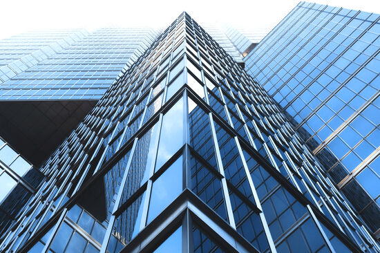 Looking up from the ground at a modern glass office building’s façade